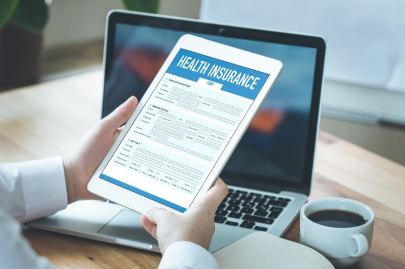 Person using tablet to fill online health insurance form.